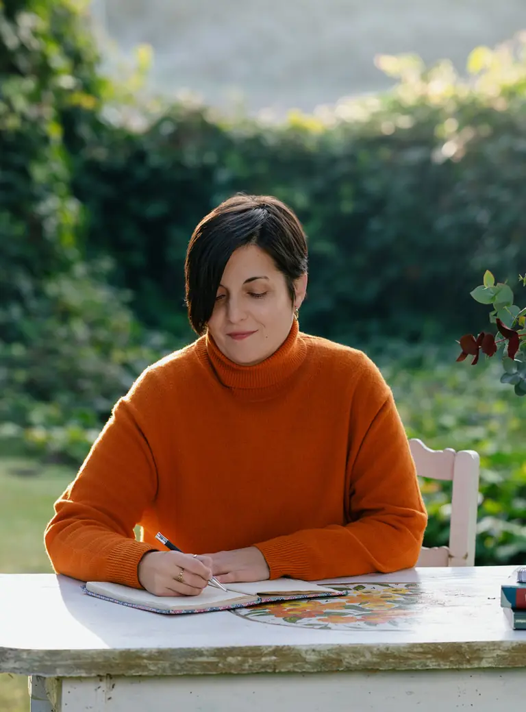 Laura Rabot escribiendo en una mesa de jardín